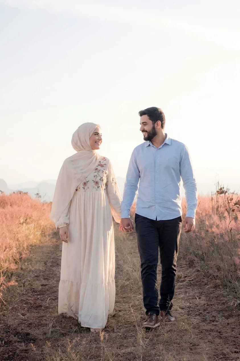 عروسان يسيران في حقلٍ عند الغروب